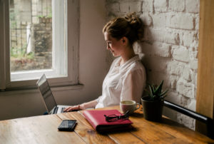 Girl blogging on her laptop in a cosy corner